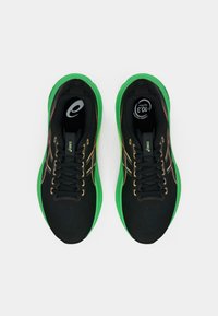 Scarpe sportive nere con suola verde, caratterizzate da una tomaia texturizzata, lacci neri e accenti decorativi in oro e rosso.