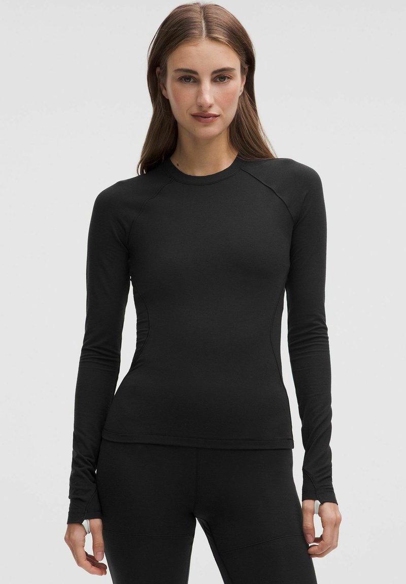 Must musta pikkade varrukatega spordipusa venivast kangast, ümmarguse kaelusega ja raglanvarrukatega, et tagada liikumisvabadus.