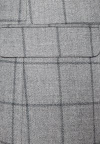 Szary woskowany materiał w kratkę z delikatną teksturą, z kieszenią na piersi oraz przecinającymi się cienkimi czarnymi i białymi liniami.