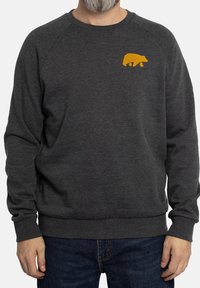 Sudadera gris oscura con mangas largas, puños acanalados y un diseño de oso amarillo en el pecho. Textura suave, ajuste casual y escote redondeado.