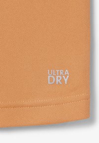 Tissu texturé marron clair avec ourlet cousu et texte brodé en blanc "ULTRA DRY" près du bord inférieur.