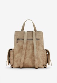 Sac à dos en synthétique de couleur tan avec un design structuré, poche arrière zippée, poches latérales et deux poignées supérieures. Texture plate avec un léger éclat.