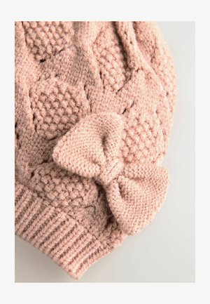 Cappello lavorato a maglia di colore rosa con un motivo testurizzato caratterizzato da esagoni in rilievo e un grande fiocco decorativo sul lato. Filato morbido e fascia a coste.