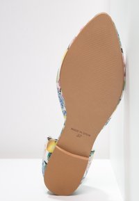Chaussure à motif floral avec une semelle lisse de couleur claire. Le dessus présente un mélange vibrant de couleurs et de textures, marqué "Fabriqué en Espagne" et taille 37.