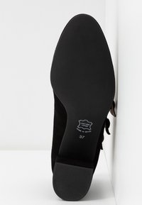 Czarna zamszowa podeszwa buta o gładkim wykończeniu, z niewielkim obcasem i wytłoczonym oznaczeniem wskazującym rozmiar 37 oraz materiał skórzany.