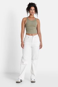 Groen geribbelde crop top met geplooide zijkanten, gecombineerd met hoogsluitende witte rechte jeans. Model staat tegen een witte achtergrond.