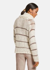 Chunky gebreid sweater in crème met bruine strepen, met een hoge kraag en een losse pasvorm, die een gestructureerd, open geweven ontwerp benadrukt.