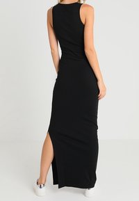 Musta maksimekko ilman hihoja, vartalonmyötäinen malli, sivuhalkio ja ribattu pinta. Yhdistetty valkoisiin tennareihin.