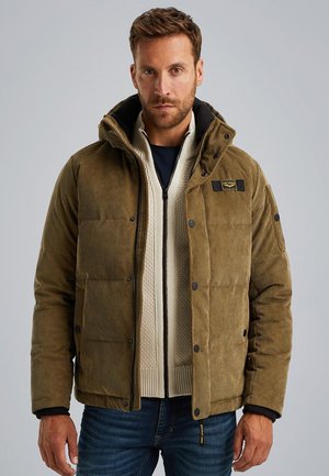 Brown corduroy puffer jacket with a detachable hood, black accents, and button closures over a cream knit sweater and dark jeans.