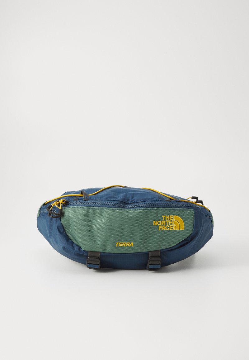 Marsupio realizzato in nylon testurizzato blu e verde, con dettagli gialli, zip frontale e accessori neri. Mostra "THE NORTH FACE" e "TERRA."