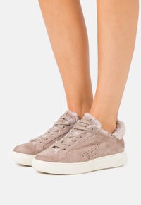 Zapatillas de ante beige con un suave cuello de un beis claro, cierre de cordones y detalles perforados en los laterales. Suela de goma blanca.
