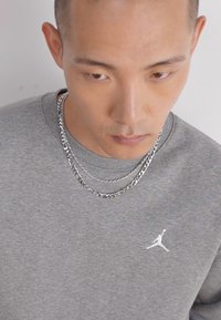 Felpa grigia con logo Jumpman bianco, stratificata con due catene d'argento, dotata di una texture liscia e scollo rotondo.