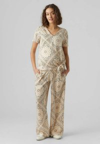 Lättvikts lounge-set i beige med blommiga och geometriska mönster. Inkluderar en V-ringad topp och lösa, bälteklädda vida byxor.