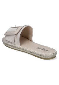 Light beige slide sandal with a wide strap featuring a decorative rectangular buckle, soft suede material, and braided jute sole.