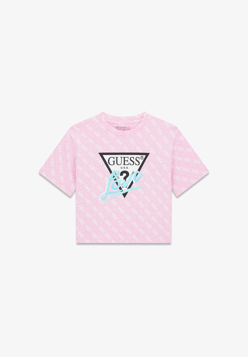 Maglietta rosa ritagliata con motivo a logo ripetuto, grande triangolo nero con scritta "GUESS" e "Love" in corsivo blu.