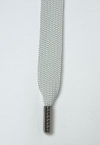 Grau gewebtes Schuhband mit strukturiertem Oberflächen, versehen mit einem metallenen Endstück, das mit "ELBSAND" graviert ist. Glattes und flaches Design.