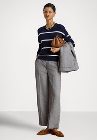 Μπλε ναυτικό πουλόβερ με ρίγες, ανοιχτό γκρι παντελόνια προσαρμοσμένης ραφής, καφέ δερμάτινη τσάντα και ταμπά λοφάδες. Περιλαμβάνει γκρι σακάκι που κρέμεται στο χέρι.