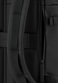 Mochila negra con respaldo de malla texturizada, correas acolchadas, tela lisa y un compartimento con cremallera que presenta un tirador de cremallera de marca.