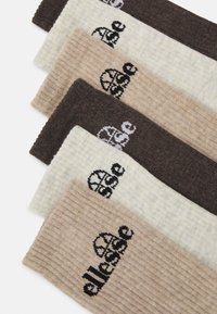 Set di calze a coste in tonalità di beige e marrone, con un design del logo in nero. Ogni calza mostra variazioni di colore e texture distinte.