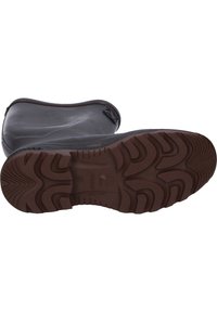 Botte en caoutchouc noire et imperméable avec une semelle extérieure épaisse de couleur brune dotée d'un motif de grip texturé. Tige lisse avec un design de pointe arrondie.
