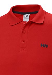Polo rojo con tejido texturizado, tres botones, un acento de cuello negro y un pequeño logo azul en el lado izquierdo.