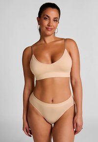 Naadloze bh in nude kleur met dunne bandjes, gecombineerd met een bijpassende hoge taille bikini broekje. Zachte, rekbare stof met een gladde textuur.