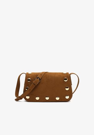 Sac à bandoulière en daim marron avec des clous ronds dorés le long des bords et une sangle ajustable avec une boucle en métal.