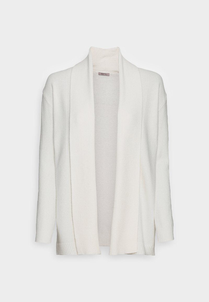 Cardigan blanc ouvert sur le devant avec manches longues et col châle côtelé, présenté sur un fond uni.