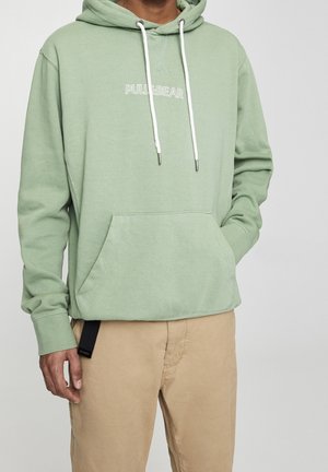 Haut à capuche vert clair avec des cordons blancs et une poche kangourou avant. Présente le logo "PULL&BEAR" en blanc, affiché sur la zone de la poitrine.