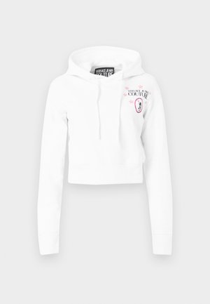 Sweat à capuche court blanc à manches longues, capuche avec cordon de serrage, et logo rose "Versace Jeans Couture" avec étoiles et emblème de Méduse sur la poitrine.