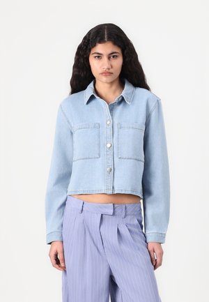 Giacca di jeans azzurro chiaro, corta, con maniche lunghe, due tasche sul petto e chiusura a bottoni. Tessuto texturizzato con un lavaggio leggermente sbiadito.