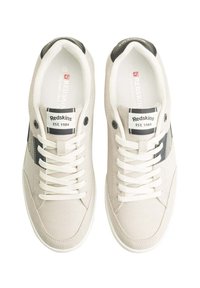 Sneaker in tela grigia chiara con lacci bianchi, dettagli neri e etichetta con logo. Punta arrotondata e tomaia testurizzata per aderenza e comfort.