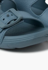 Sandal in sintetico blu con fibbia regolabile, cinghia texturizzata e soletta sagomata. La suola presenta scanalature orizzontali per una maggiore aderenza.