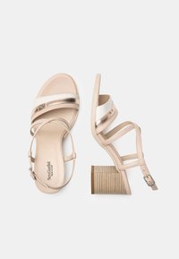 Sandali platform beige con accenti metallici, molteplici cinturini, un tacco a blocco texturizzato e una finitura in pelle liscia. Nome del marchio visibile all'interno.