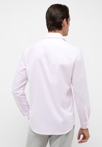 Lichtroze shirt met lange mouwen, van zachte stof met een klassieke kraag, een rugplooitje, een gebogen zoom en knoopmanchetten. Aangepaste pasvorm.