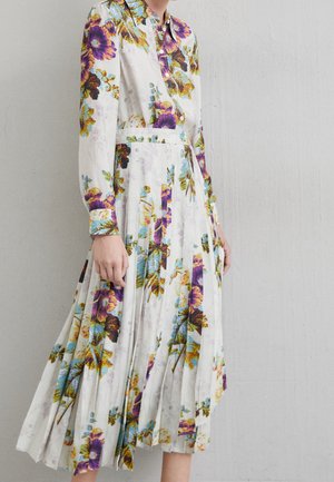 Blumenmuster-Kleid mit weißem Grund, ausgestattet mit langen Ärmeln, einem Kragen, einem plissierten Rock und detaillierten Knopfakzenten in kontrastierenden Farben.