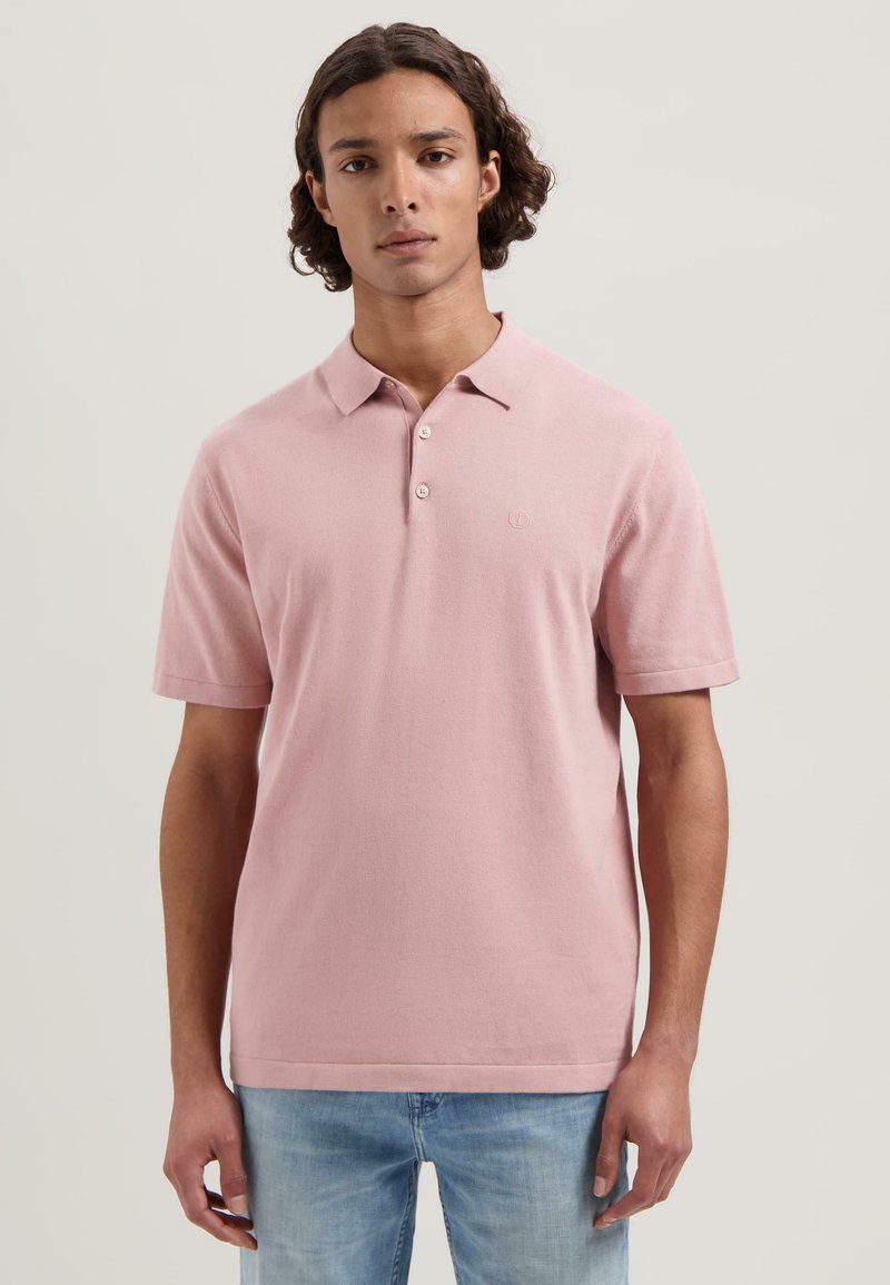 Polo shirt rosa a maniche corte realizzato in tessuto morbido, dotato di colletto, pattina con tre bottoni e logo ricamato sul petto.