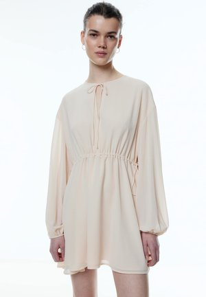 Kurzärmliges, blassrosa Kleid mit elastischem Bund und Bindeband am Hals. Verfügt über weit ausgestellte Ärmel und eine glatte, fließende Textur.