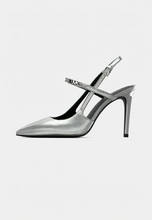 Zilveren slingback hoge hakken met een puntige neus, glanzende afwerking en een dunne naaldhak. Decoratieve band met metalen accenten.