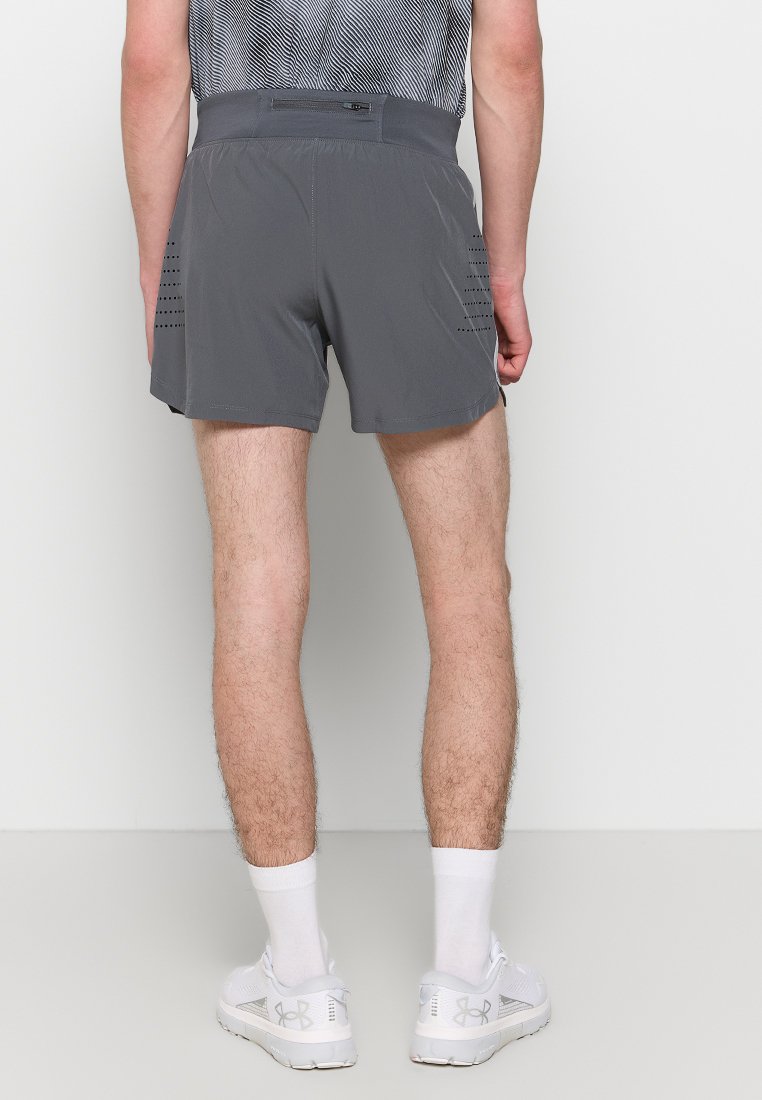 Pantaloncini sportivi grigi realizzati in materiale leggero, con una fascia in vita e dettagli laterali perforati. Abbinati a scarpe sportive bianche.