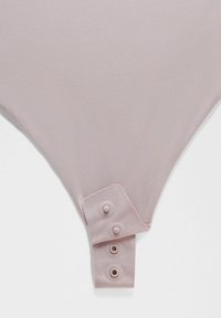 Bodysuit rose clair avec une texture lisse, doté d'une patte de boutonnage avec trois pressions et d'un design à jambes hautes.