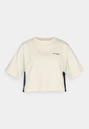 Krémové skrátené tričko s okrúhlym výstrihom, krátkymi rukávmi a čiernymi bočnými panelmi; obsahuje malé čierne logo na hrudi.