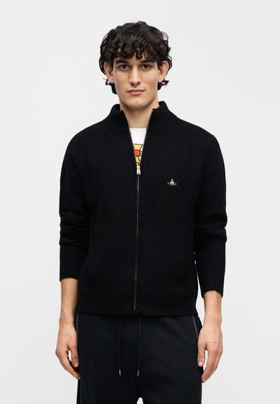 Μαύρο πλεκτό πουλόβερ με φερμουάρ, με ραβδωτή υφή, ψηλό γιακά και πλευρικές τσέπες. Διαθέτει μπλε κεντημένο λογότυπο στο στήθος.