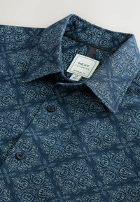 Námornícka modrá bavlnená košeľa so zakriveným paisley vzorom. Má rozšírený golier a čierne gombíky, označená ako Next Tailoring, normálny strih, veľkosť M.