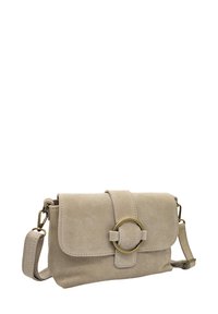 Sac bandoulière en suède beige avec fermeture à rabat, accent en matériel circulaire, bandoulière réglable et texture lisse, présentant des détails de couture.