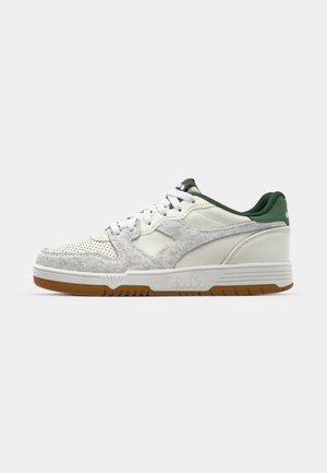 Weiß-graue Sneakers mit einer strukturierten Oberseite, die perforiertes Leder, einen grünen Akzent an der Ferse und eine Gummigummi-Außensohle aufweisen.