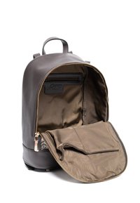 Zaino in pelle marrone con design arrotondato, apertura con cerniera e fodera interna liscia. Presenta una tasca frontale con zip per l'organizzazione.