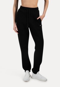 Sorte sweatpants lavet af blødt stof, med elastisk talje og snøre, sidelommer og en tætsiddende pasform. Præget med et lille logo.