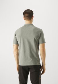 Šed�é polo tričko s krátkým rukávem, vyrobené z měkké, texturované tkaniny a s límečkem, s rovný střih a minimalistickým designem na modelu z boku.