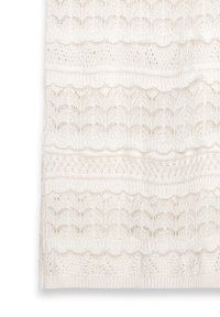 Tissu tricoté blanc avec un motif texturé de lignes ondulées et de mailles ouvertes. Comprend des sections alternées en festons et en rayures.